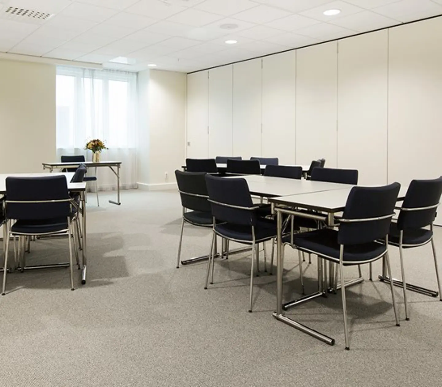 Conference room with island seating, light ceiling, light walls and black chairs