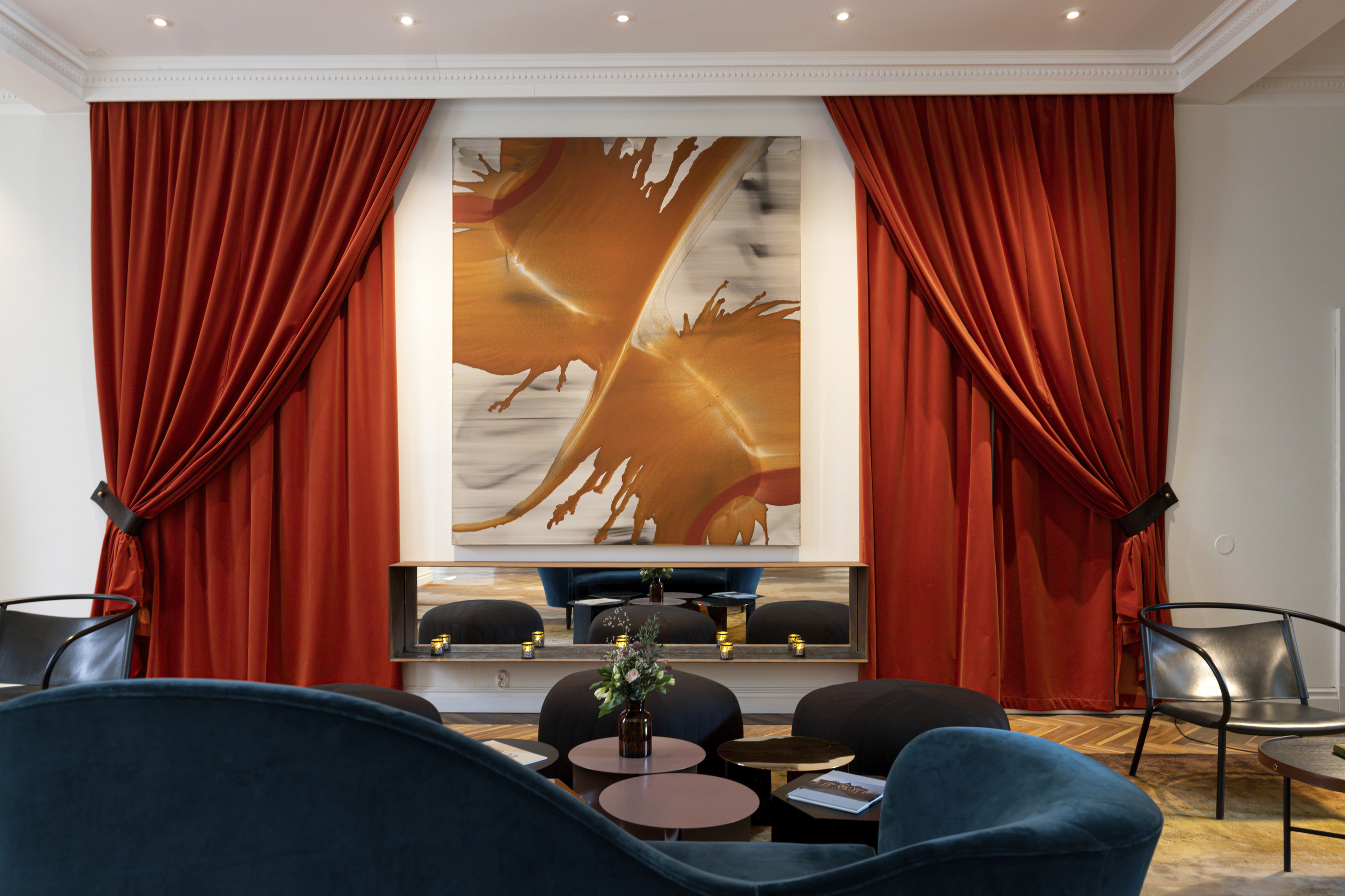 Elegant room with rich red drapes, modern abstract artwork, and stylish seating arrangement in a luxurious interior setting.