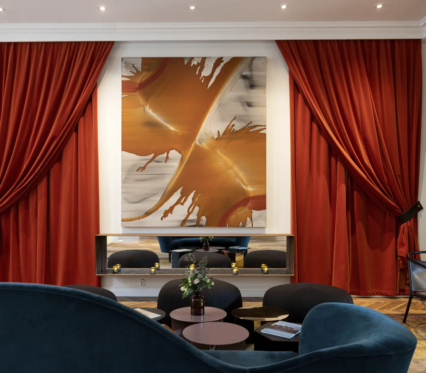 Elegant room with rich red drapes, modern abstract artwork, and stylish seating arrangement in a luxurious interior setting.