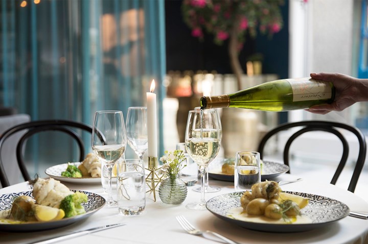 Fint uppdukad måltid med fisk, potatis och vin som hälls upp