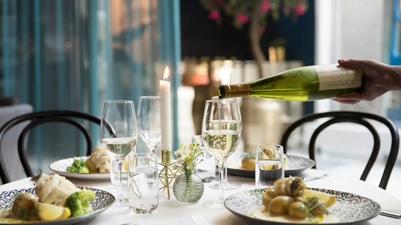 Fint uppdukad måltid med fisk, potatis och vin som hälls upp