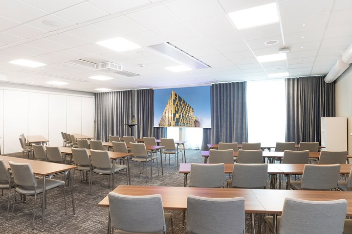 Konferensrum med skolsittning, grå stolar och vita väggar