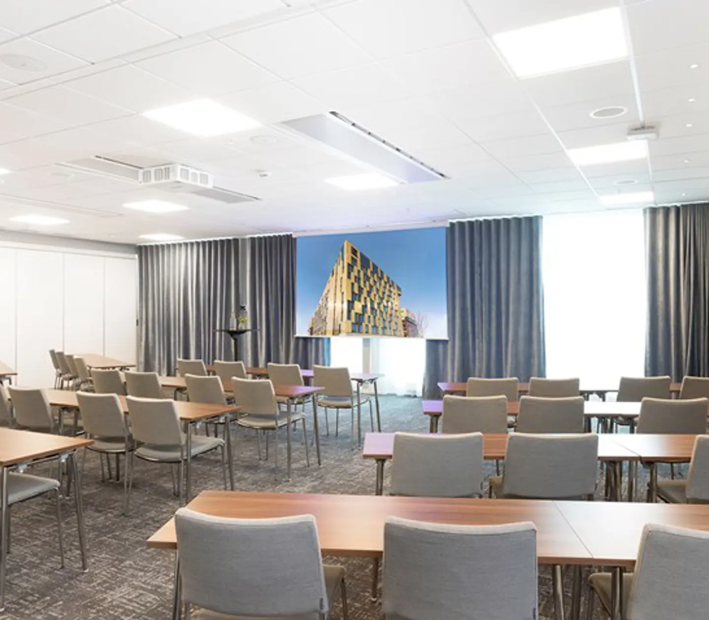Konferensrum med skolsittning, grå stolar och vita väggar