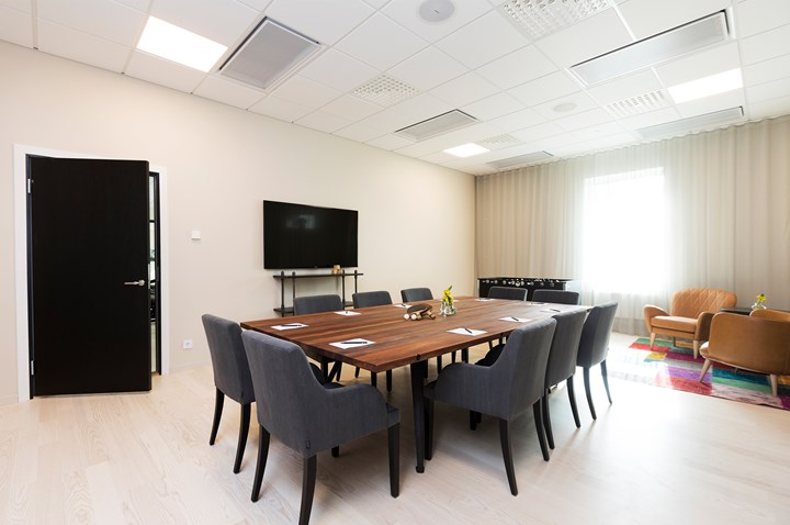 Konferensrum med styrelsesittning, brunt bord, grå fåtöljer och ljusa väggar