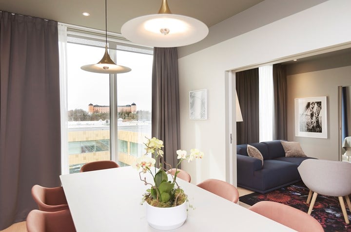 Vitt konferensbord med rosa fåtöljer, soffgrupp och fönster med utsikt