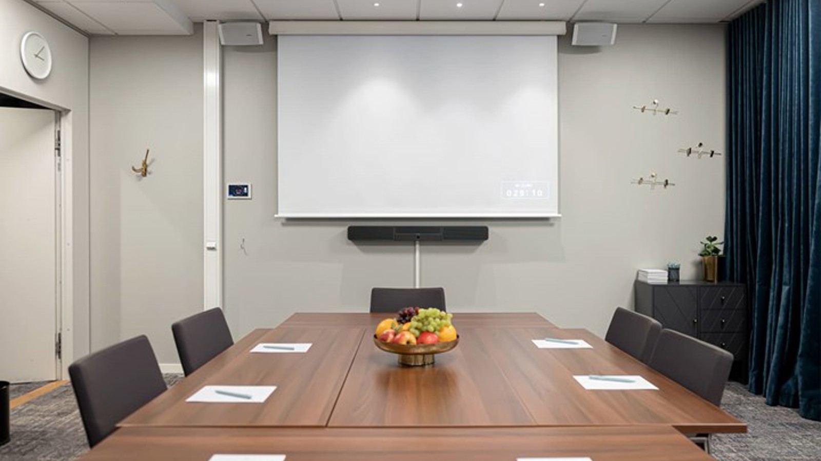 Conference room with brown table, gray chairs, light walls and a projector