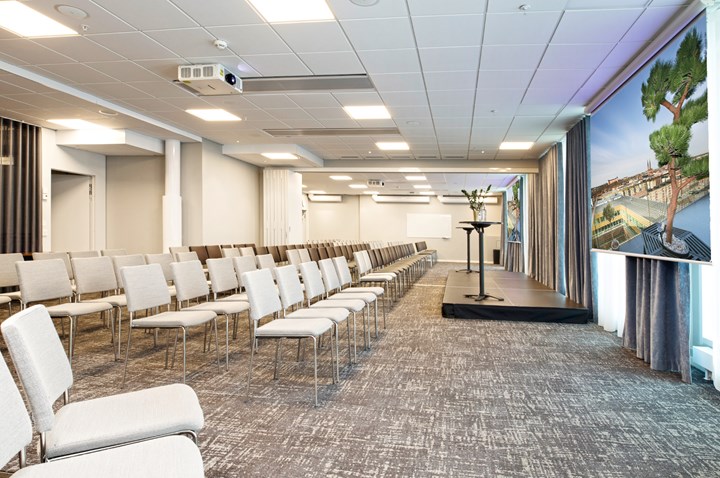 Konferensrum med biosittning, grått golv, vita stolar och vita väggar