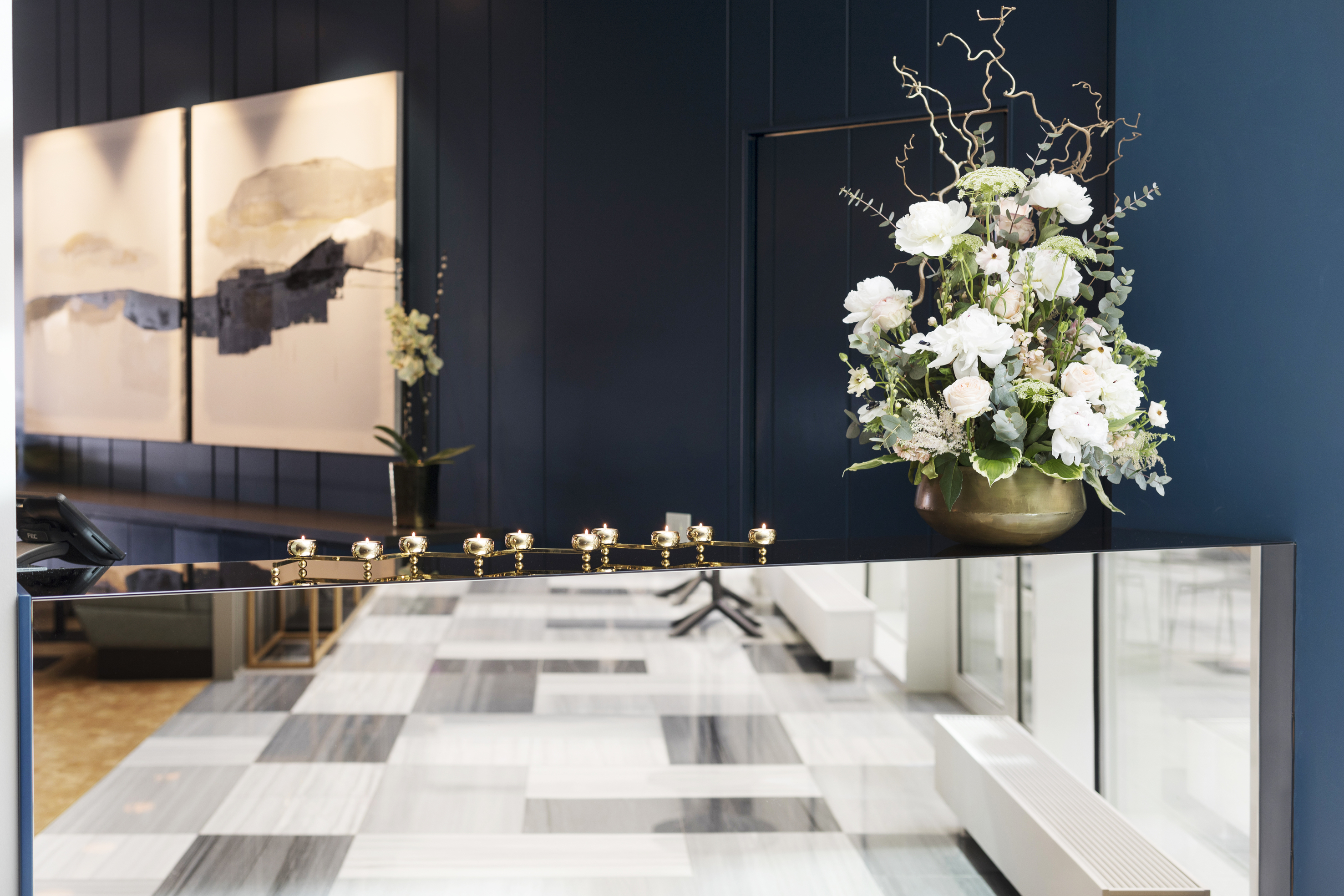 Black reception with gold details, blue wall, black and white patterned floor