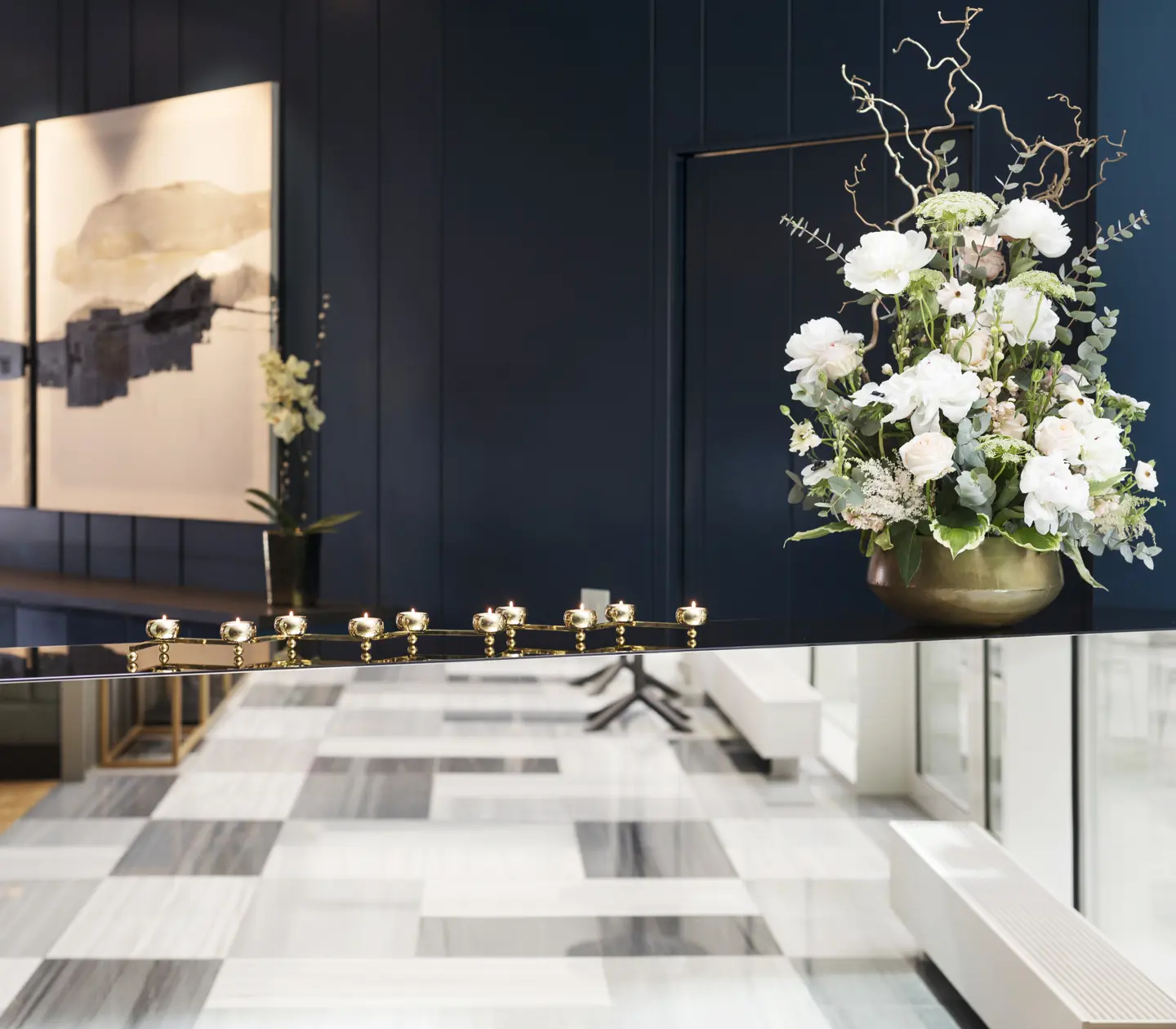 Black reception with gold details, blue wall, black and white patterned floor