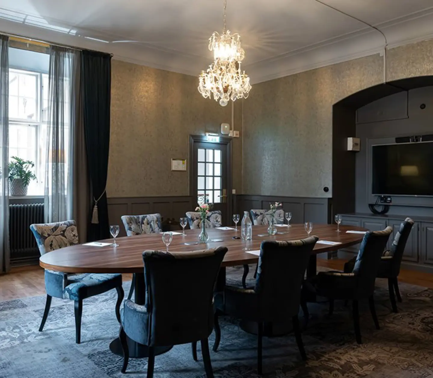 Board room with oval table, dark armchairs and gray carpet