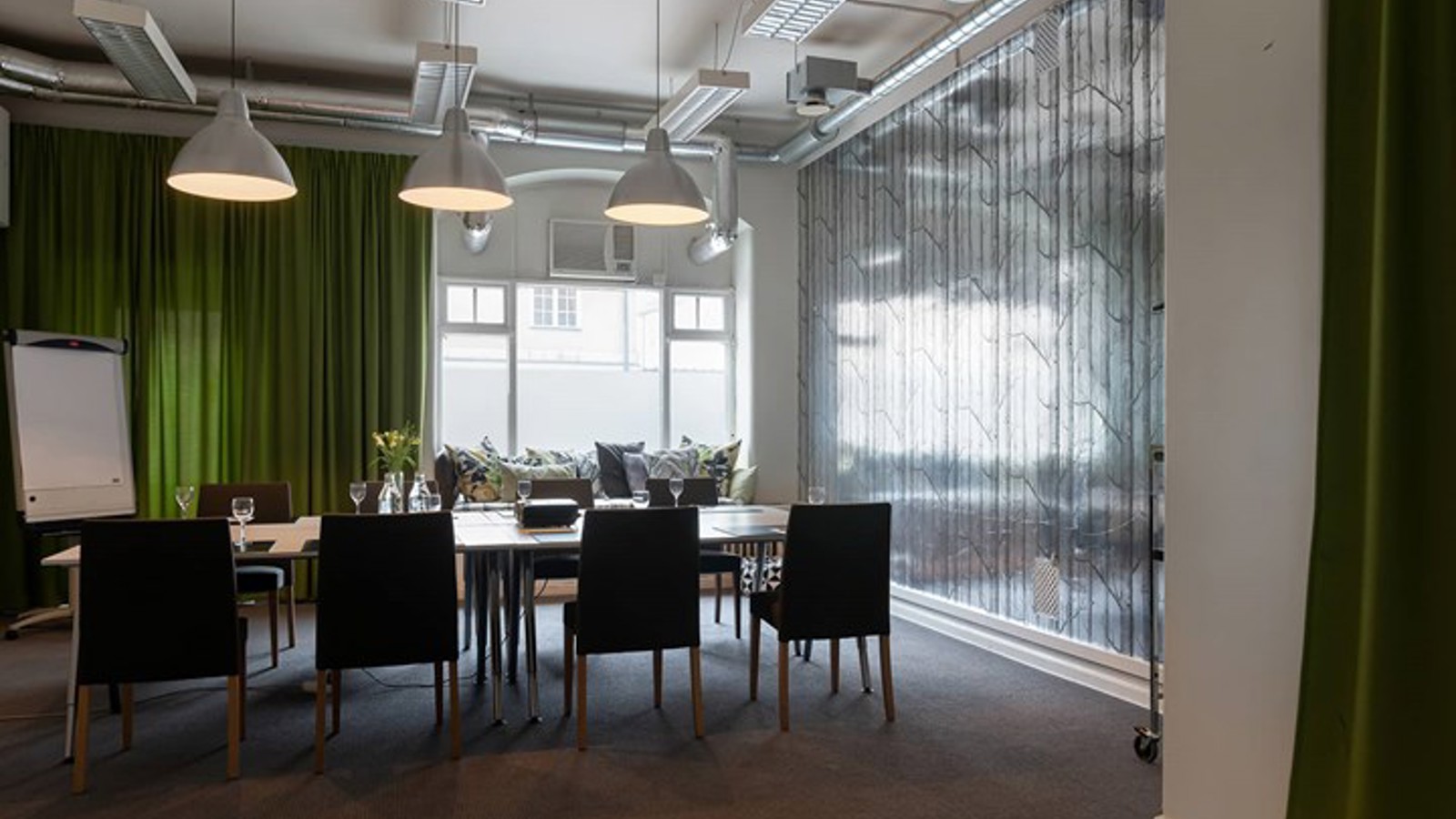 Conference room with board seating, dark chairs and green draperies
