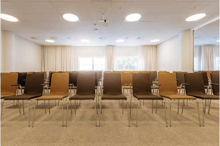 Bruna stolar uppradade i biosittning, med ljusa fönster i bakgrunden