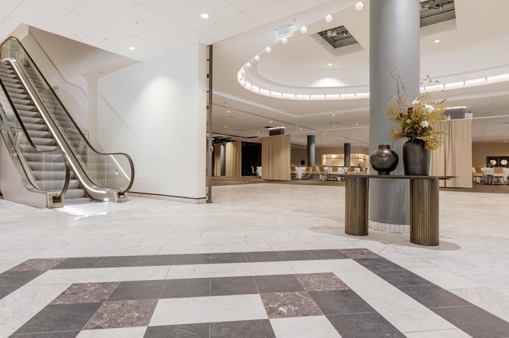 Stor öppen yta med stenlagt golv i svart och vitt, rulltrappa i bakgrunden