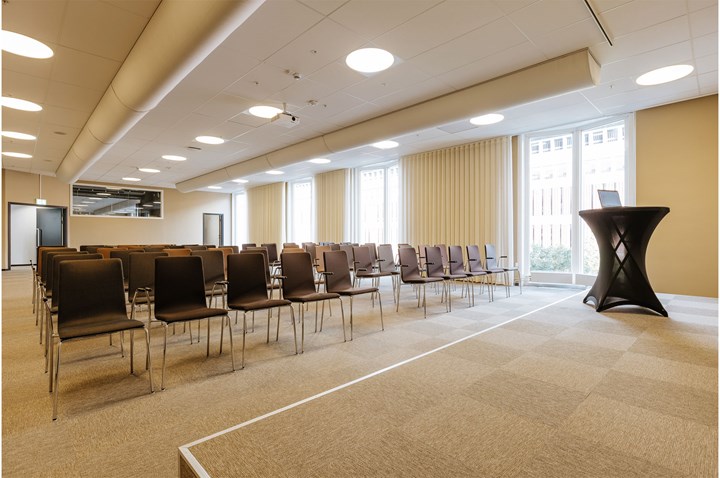 Konferenslokal med biosittning, scen och stora fönster