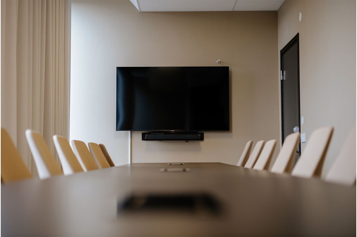 Konferensrum med styrelsesittning, brunt bord och tv-skärm