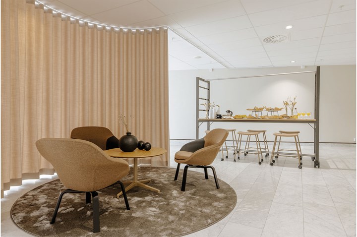 Inomhusmiljö med mindre fåtöljgrupp, rund matta och draperi