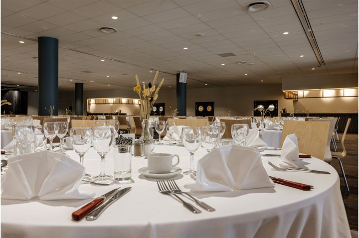 Runda bord dukade med vita dukar, servetter, glas och bestick