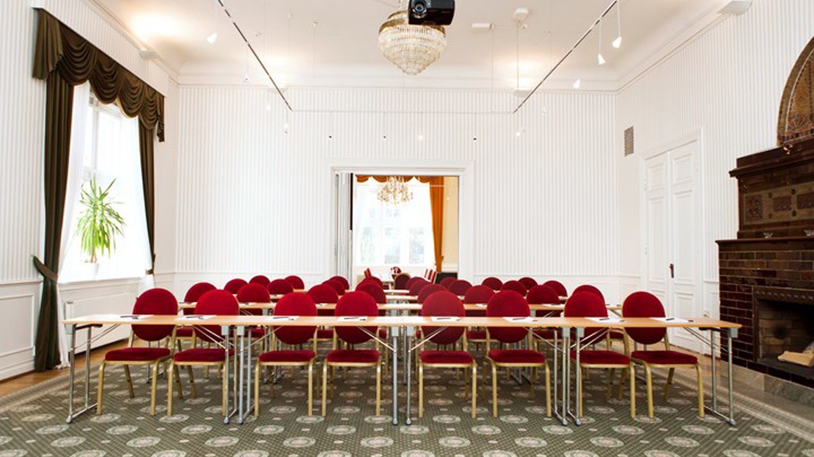 Conference room with school seating, red chairs, white walls and green patterned carpet