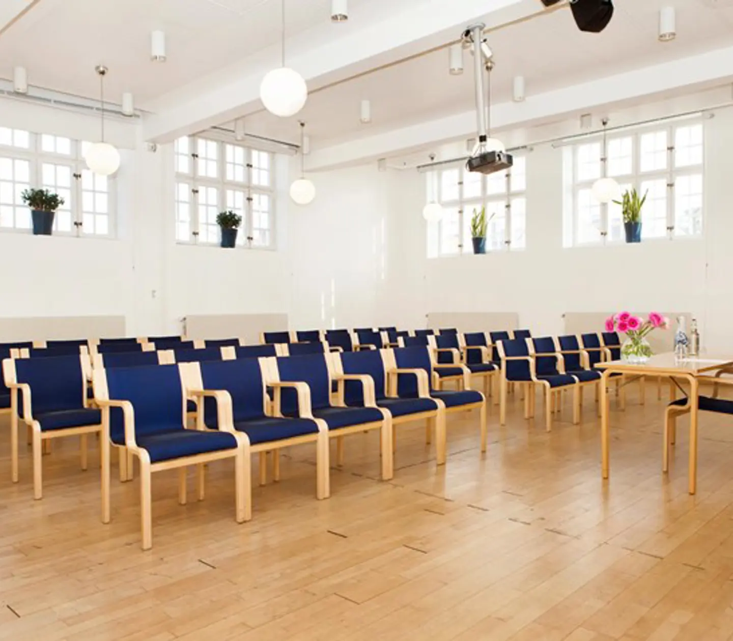 Bright conference room with cinema seating, many windows and blue chairs