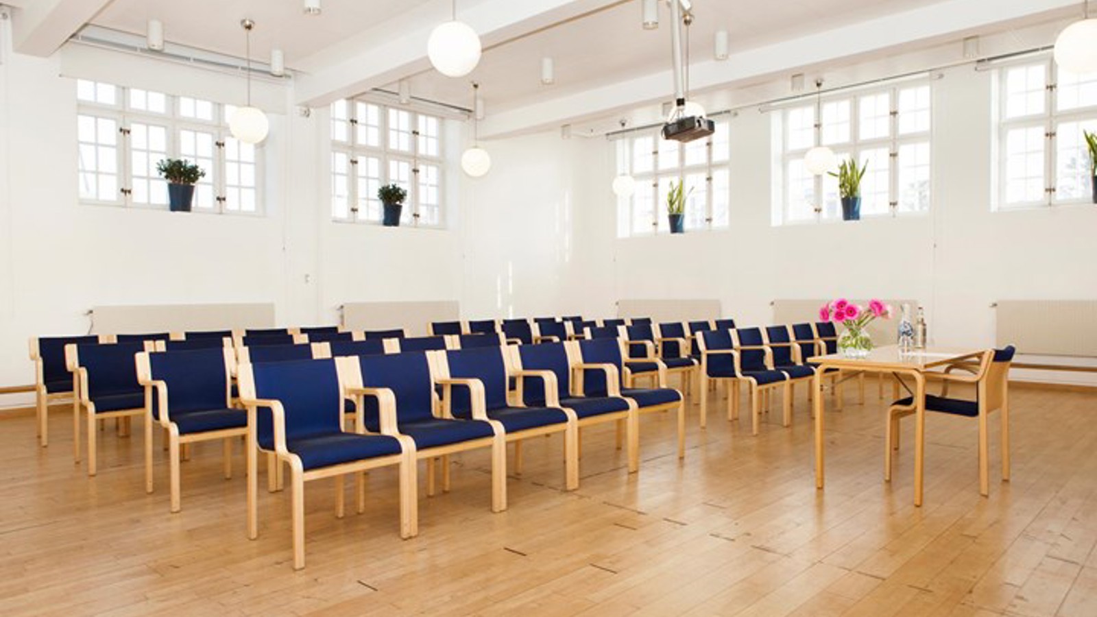 Bright conference room with cinema seating, many windows and blue chairs