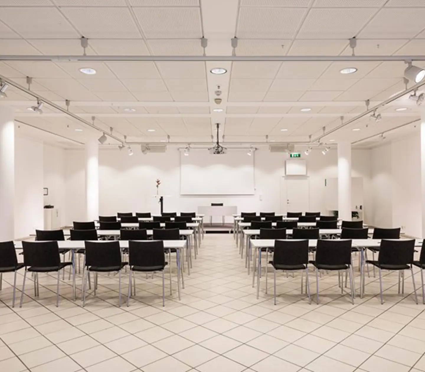 Conference room with white walls, white floor and black chairs placed in cinema seating