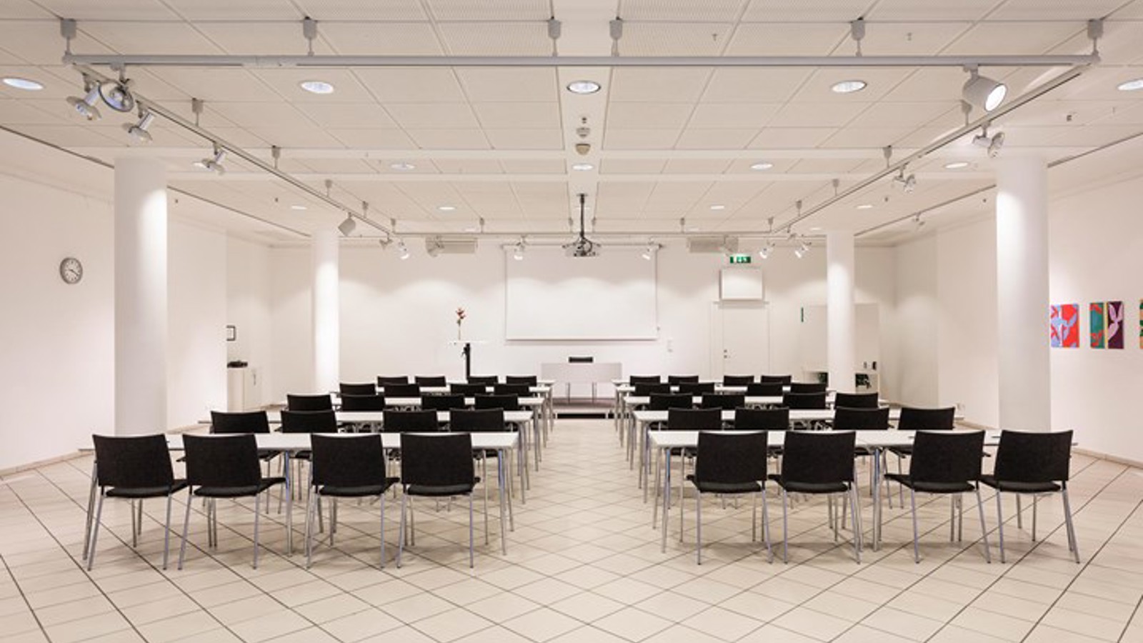 Conference room with white walls, white floor and black chairs placed in cinema seating