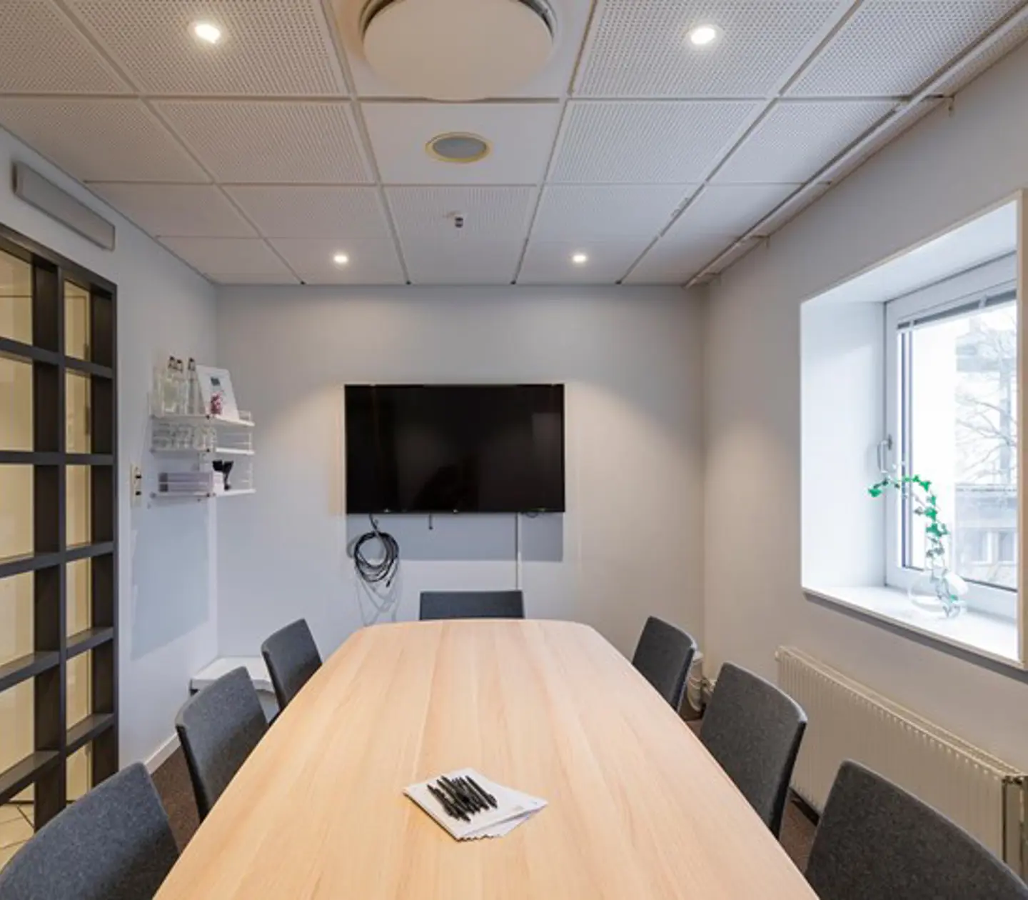 Conference room with board seating, wooden table, TV screen and window