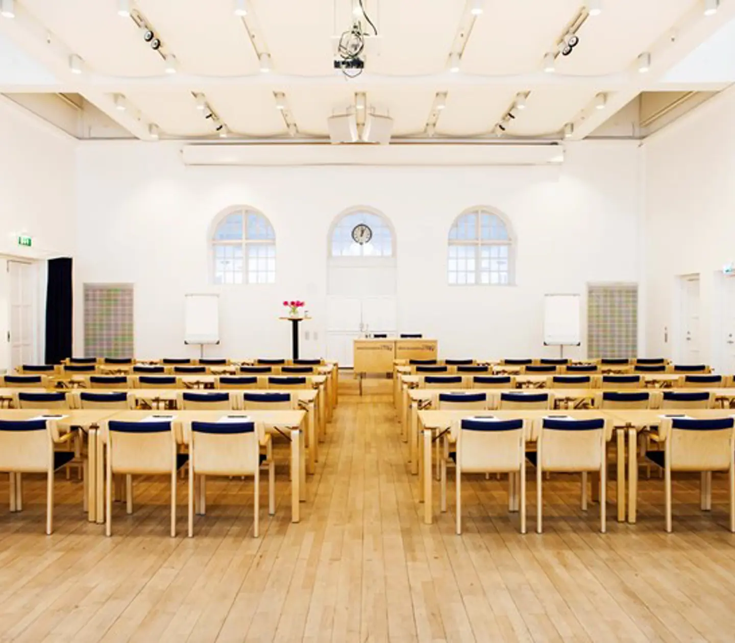 Conference with cinema seating, wooden chairs, wooden floor and white walls