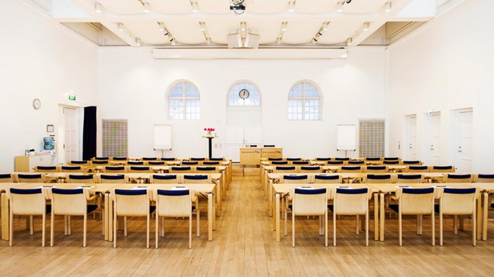 Conference with cinema seating, wooden chairs, wooden floor and white walls