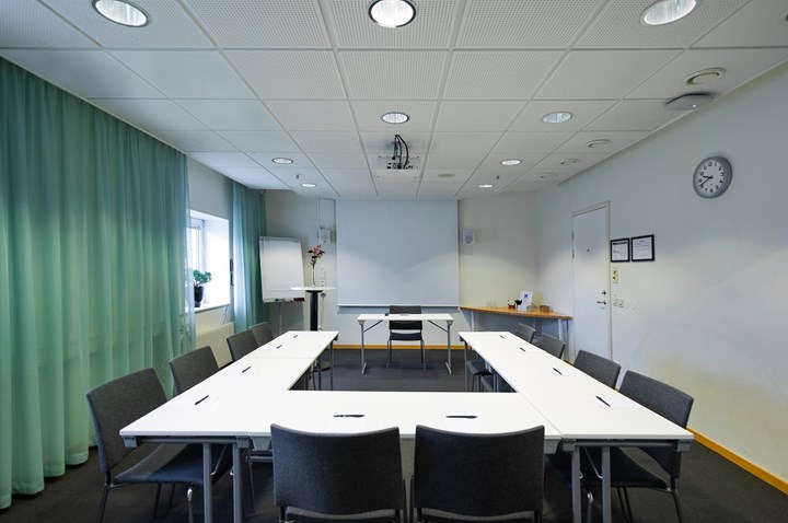 Conference room with U-shaped seating, green curtains, white table and gray chairs