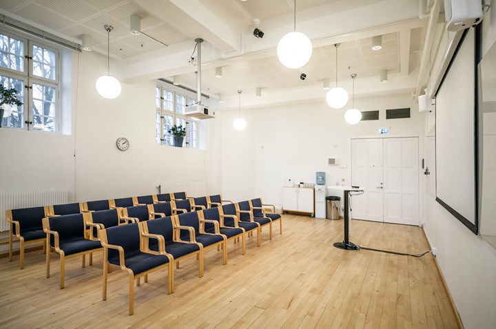 Bright conference room with dark chairs, cinema seating, projector and large windows