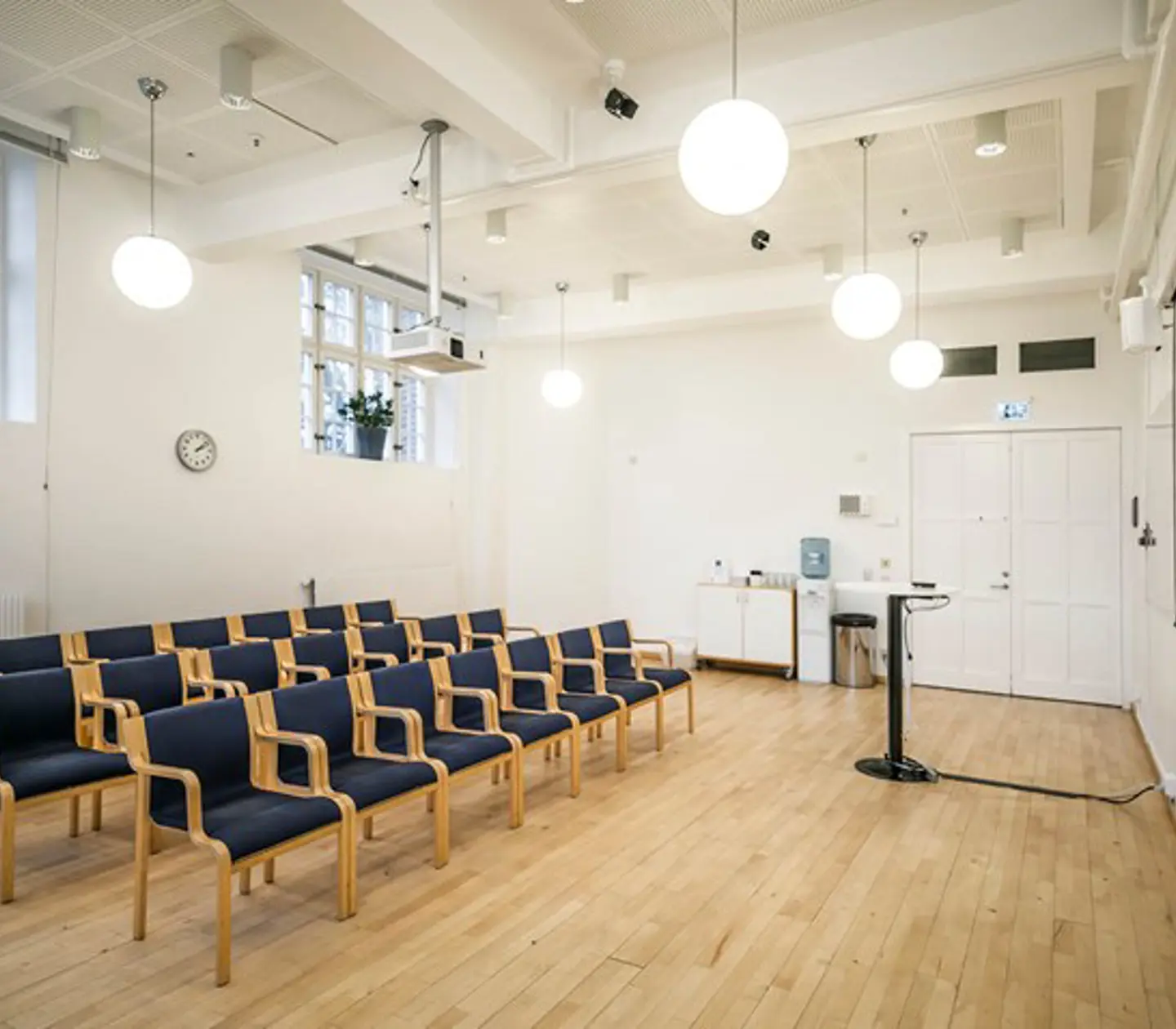 Bright conference room with dark chairs, cinema seating, projector and large windows
