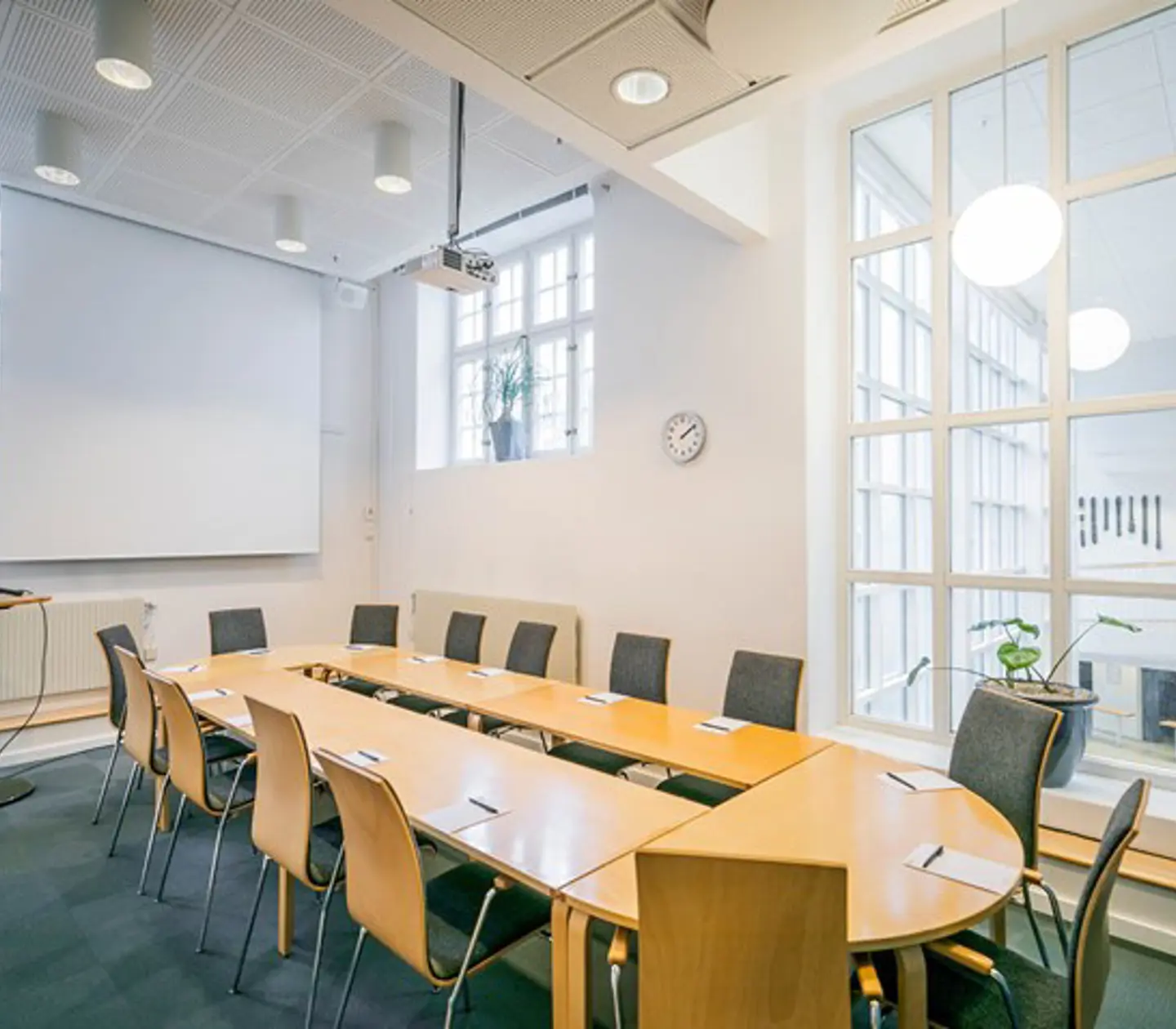 Conference room with board seating, white walls, wooden table and blue carpet