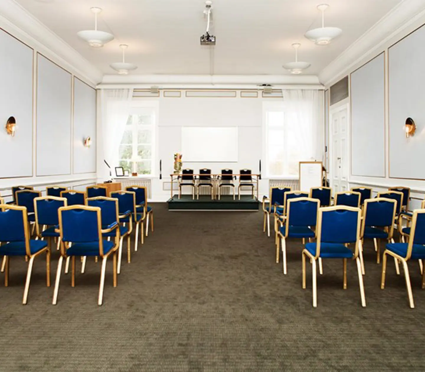 Konferenslokal med biosittning, ljusblå väggar och blå stolar