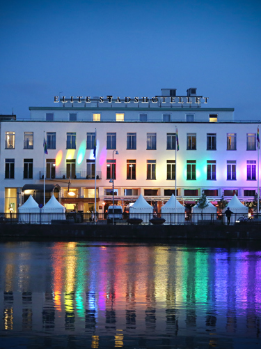 A building in Eskilstuna lights up in rainbow colors that are reflected in the lake