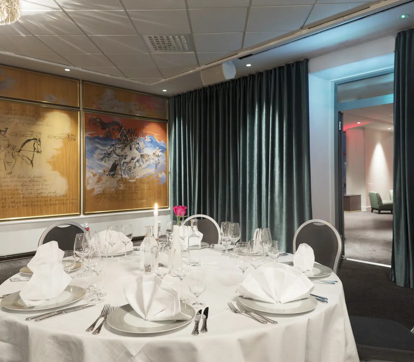 Elegant dining room setup with white linen tables, tasteful china, and modern artwork on the wall.