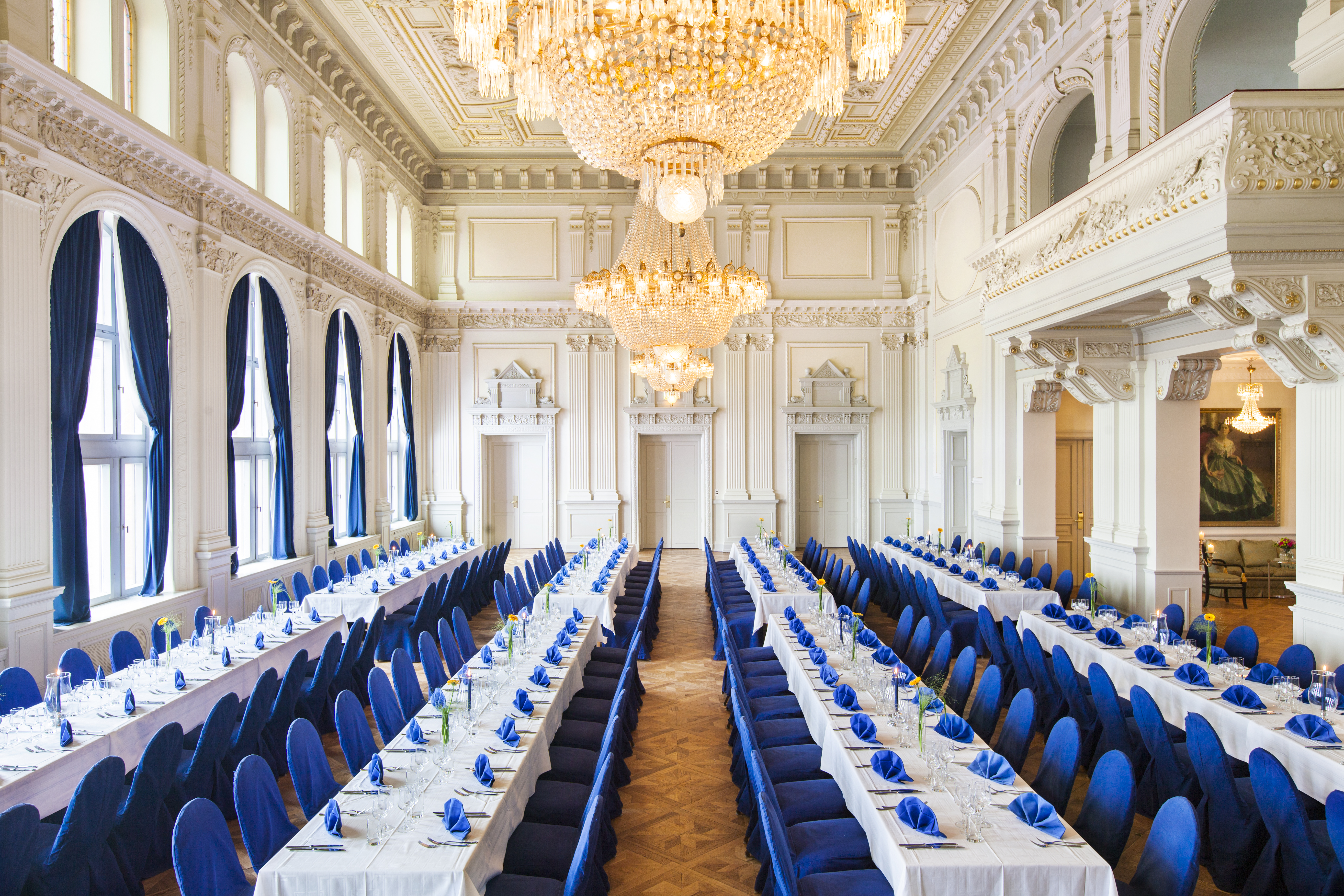 Fancy wedding hall with long tables with white tablecloths and blue chairs