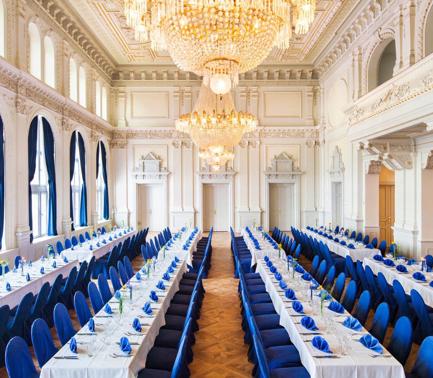 Fancy wedding hall with long tables with white tablecloths and blue chairs