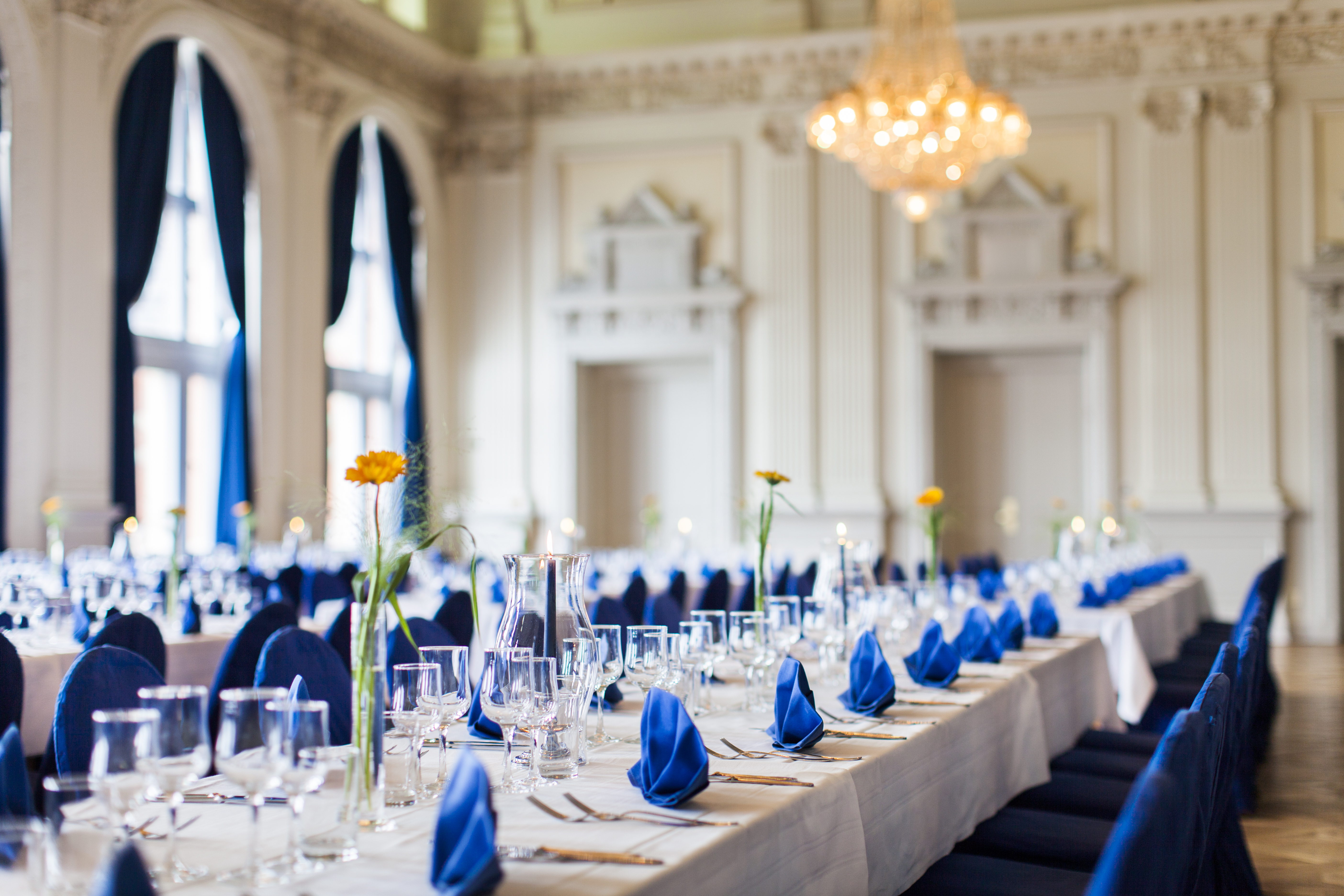 Long table in wedding venue decorated with blue napkins