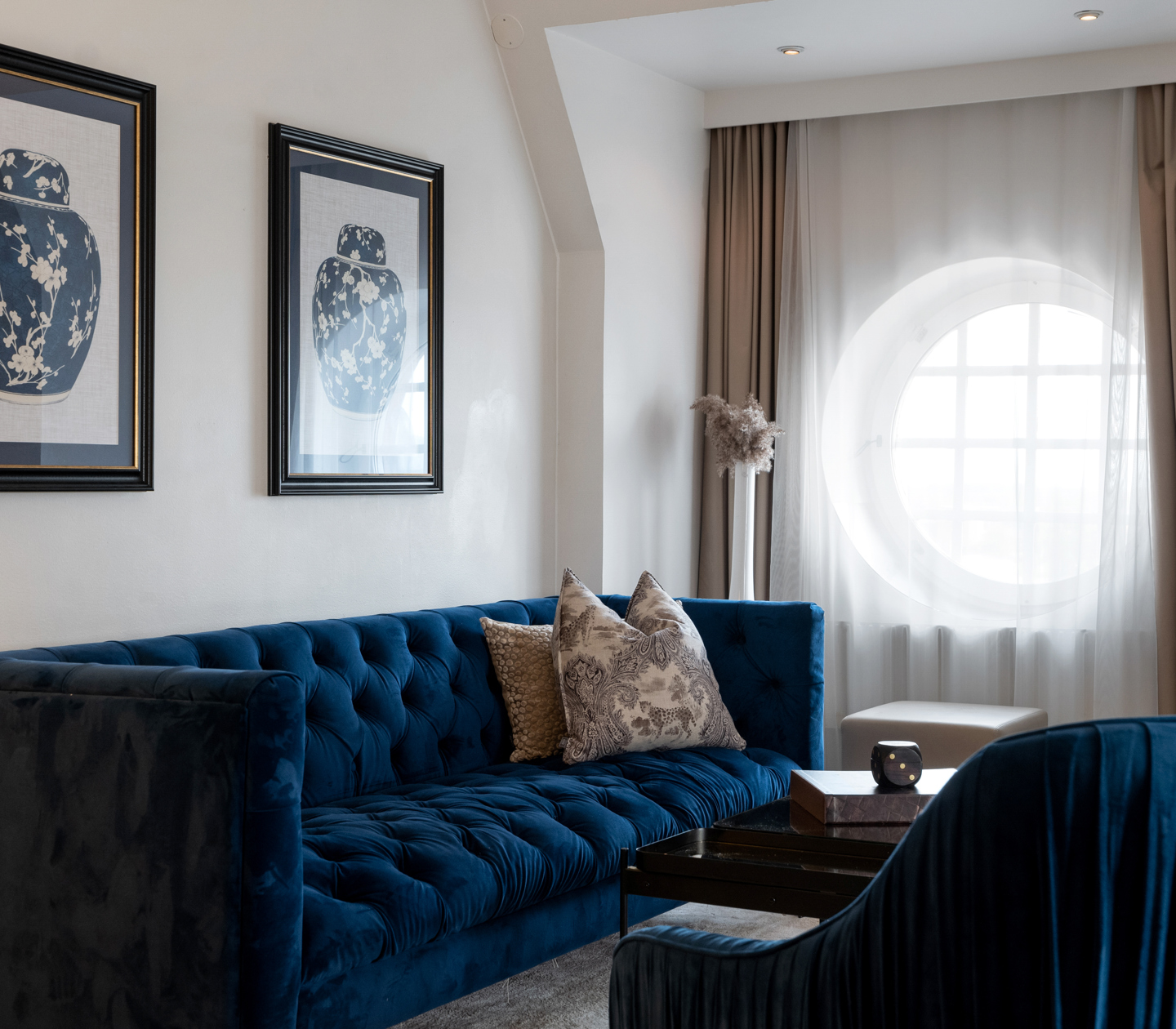 Hotel room with blue sofa group and a beautiful round window