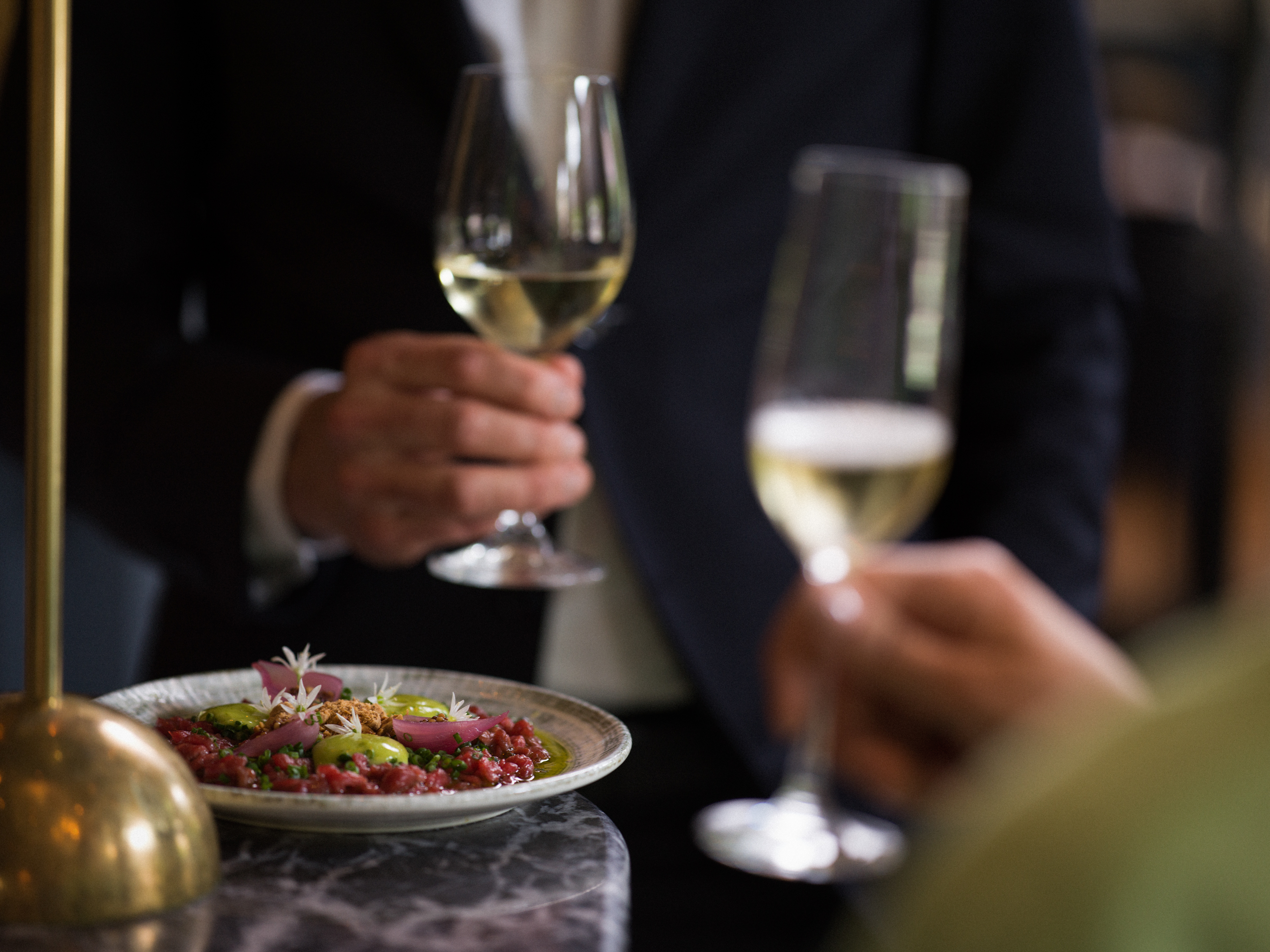 Person äter en fräsch middag i en elegant restaurang, med ett glas champagne framför sig på en marmorbordsskiva.
