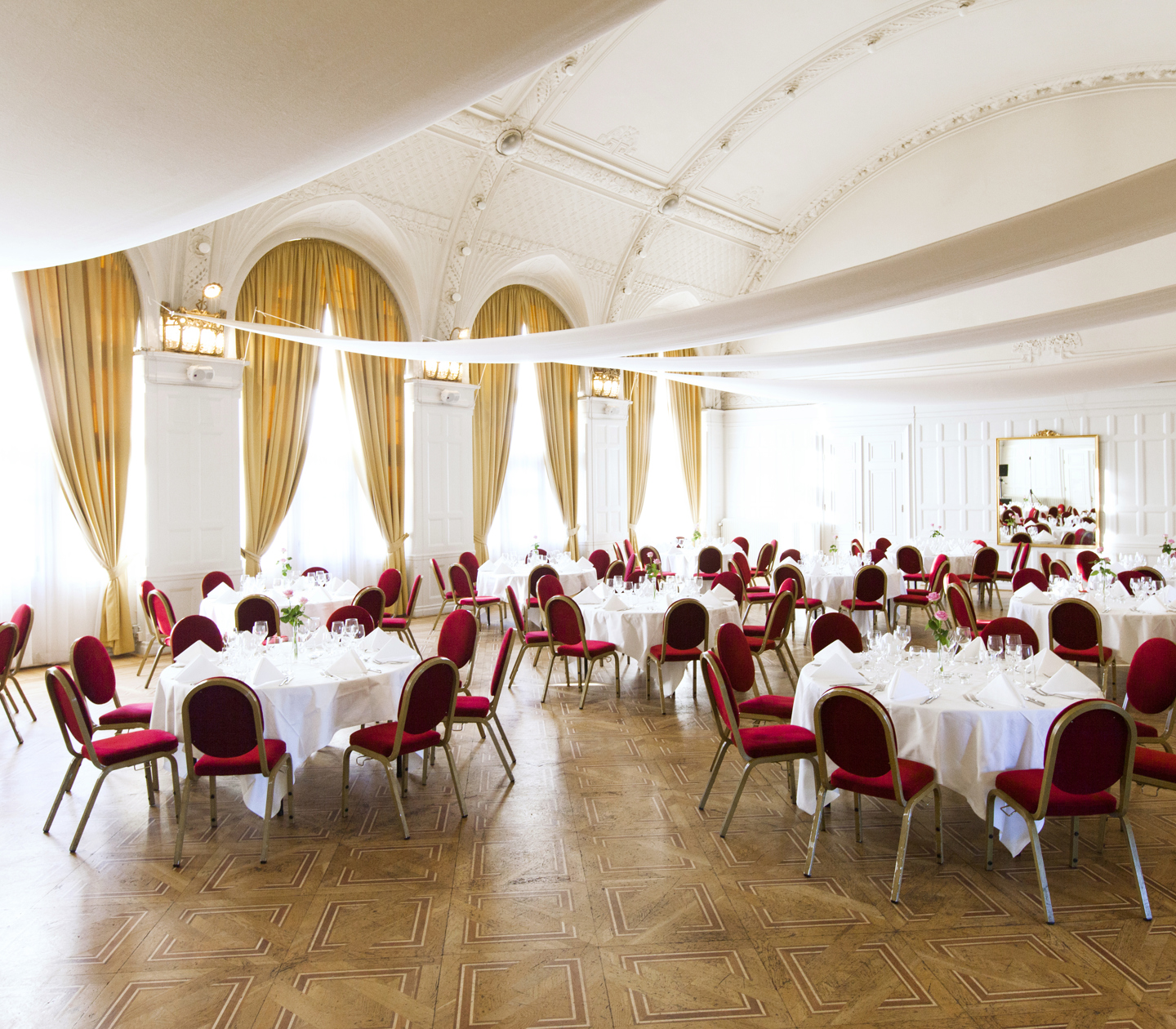 A large hall with high ceilings and round restaurant tables