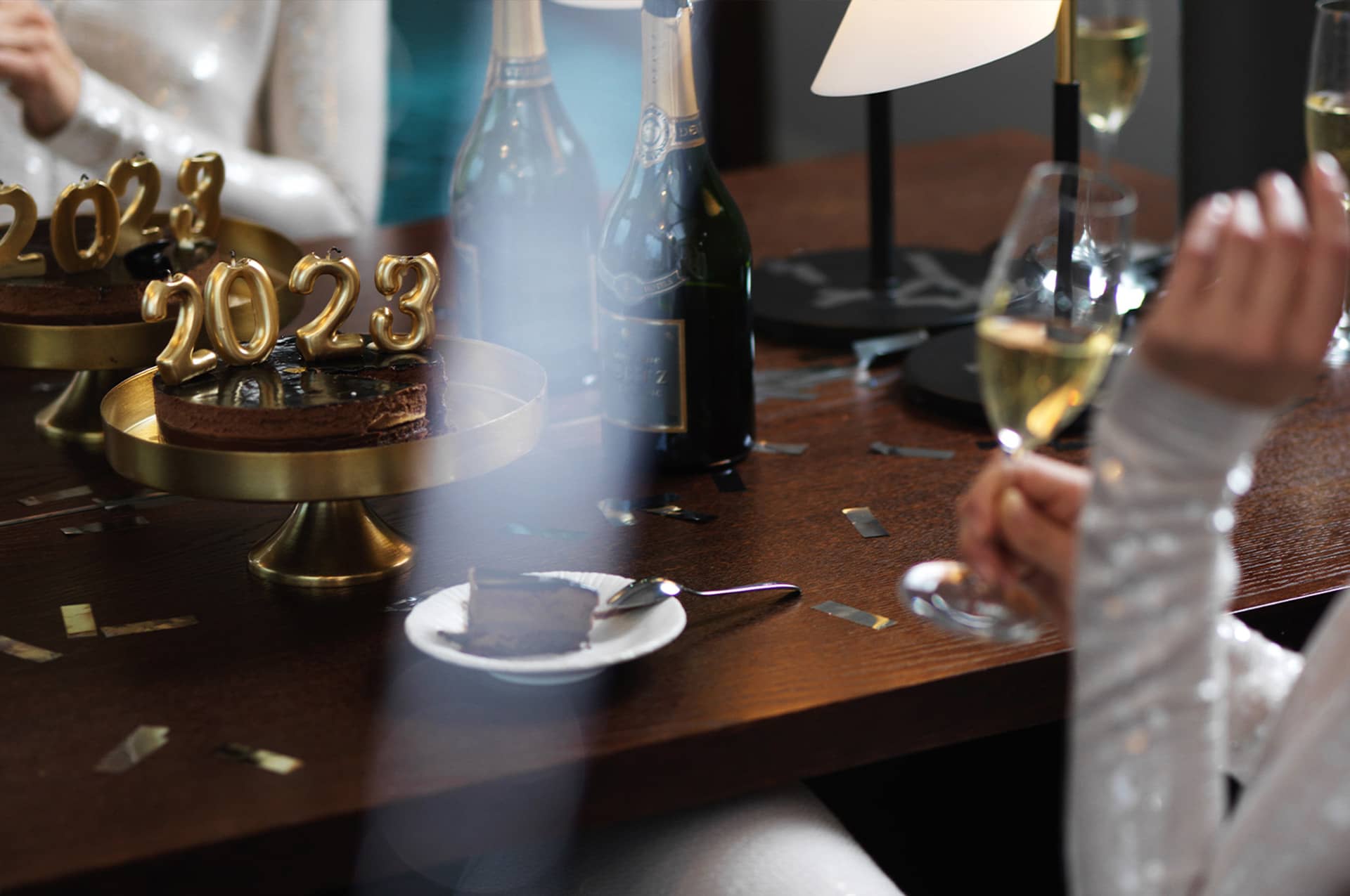 Folk sitter vid ett bord, äter tårta och dricker champagne