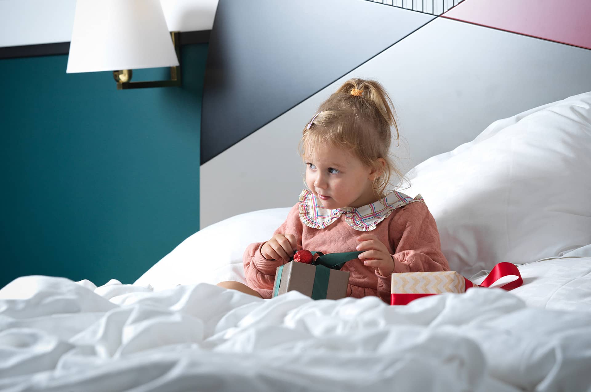 Ett barn öppnar julklappar i sängen