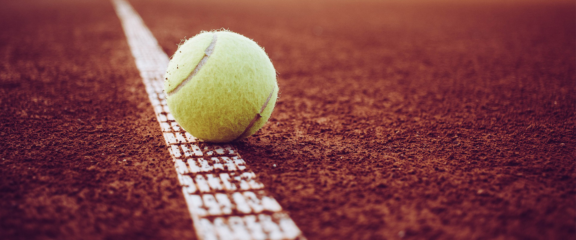 En gul tennisboll som studsar på linjen på en tennisplan