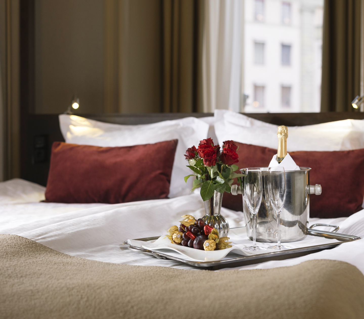 Champagne, flowers, chocolate & fruit on a hotel bed