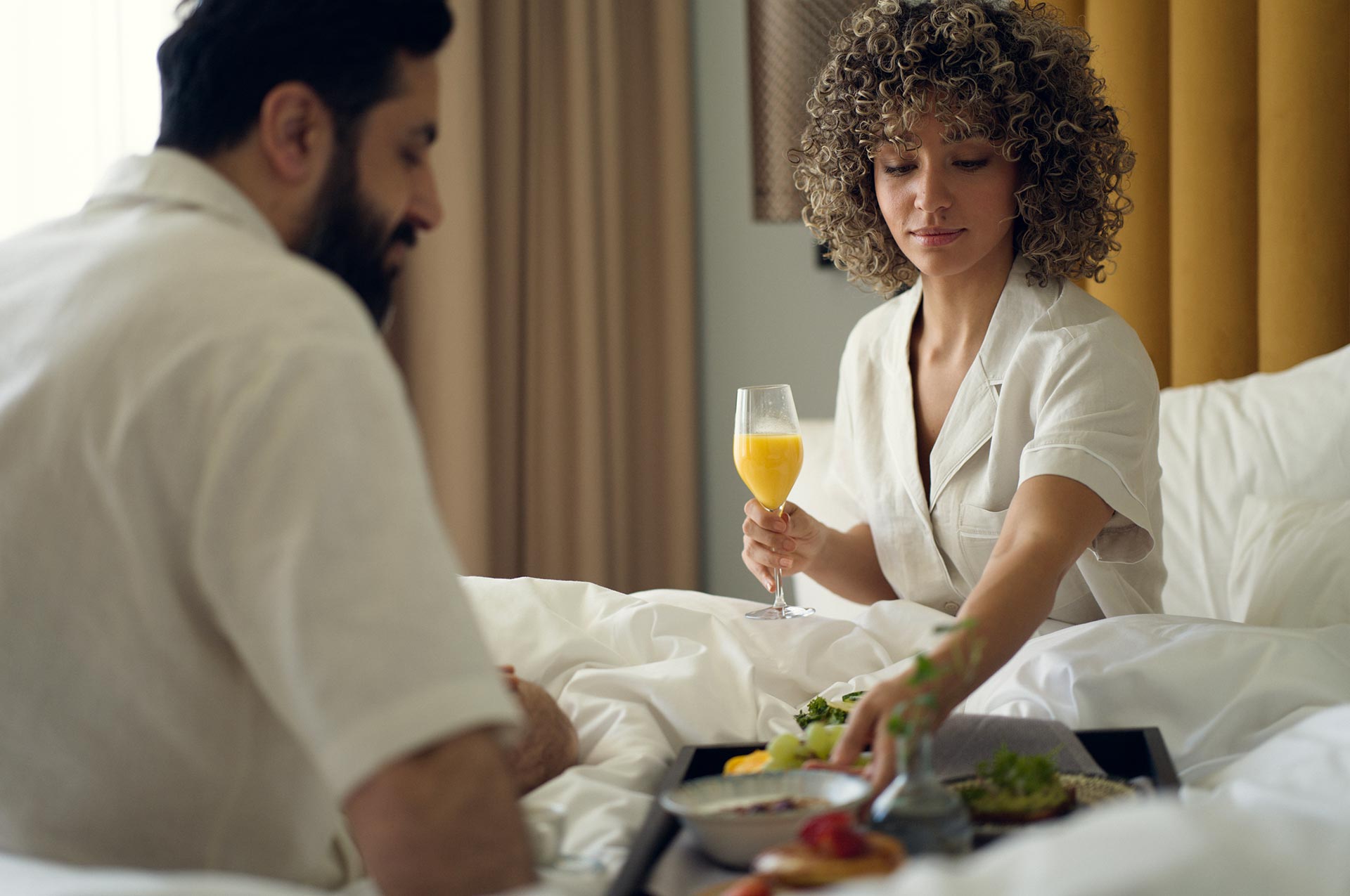 Couple eating breakfast in a hotel bed