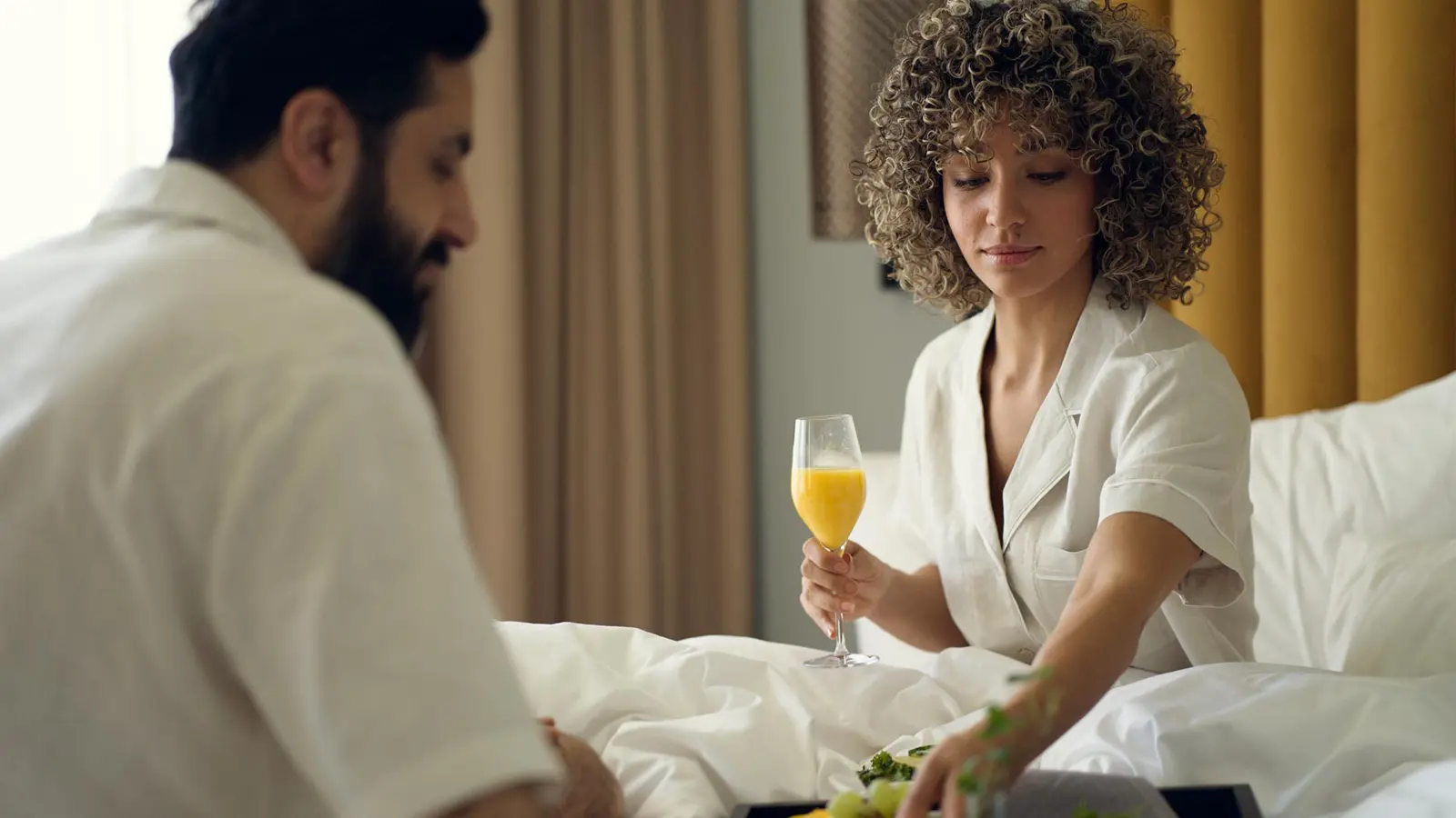 Par som äter frukost i en hotellsäng
