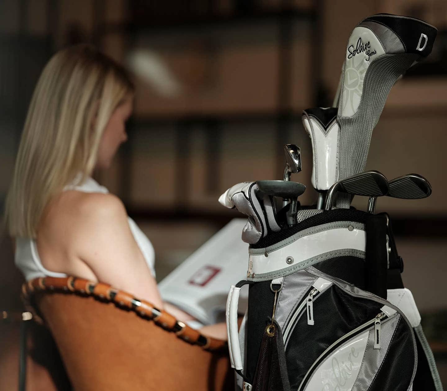 Woman with a golf bag sitting in an armchair
