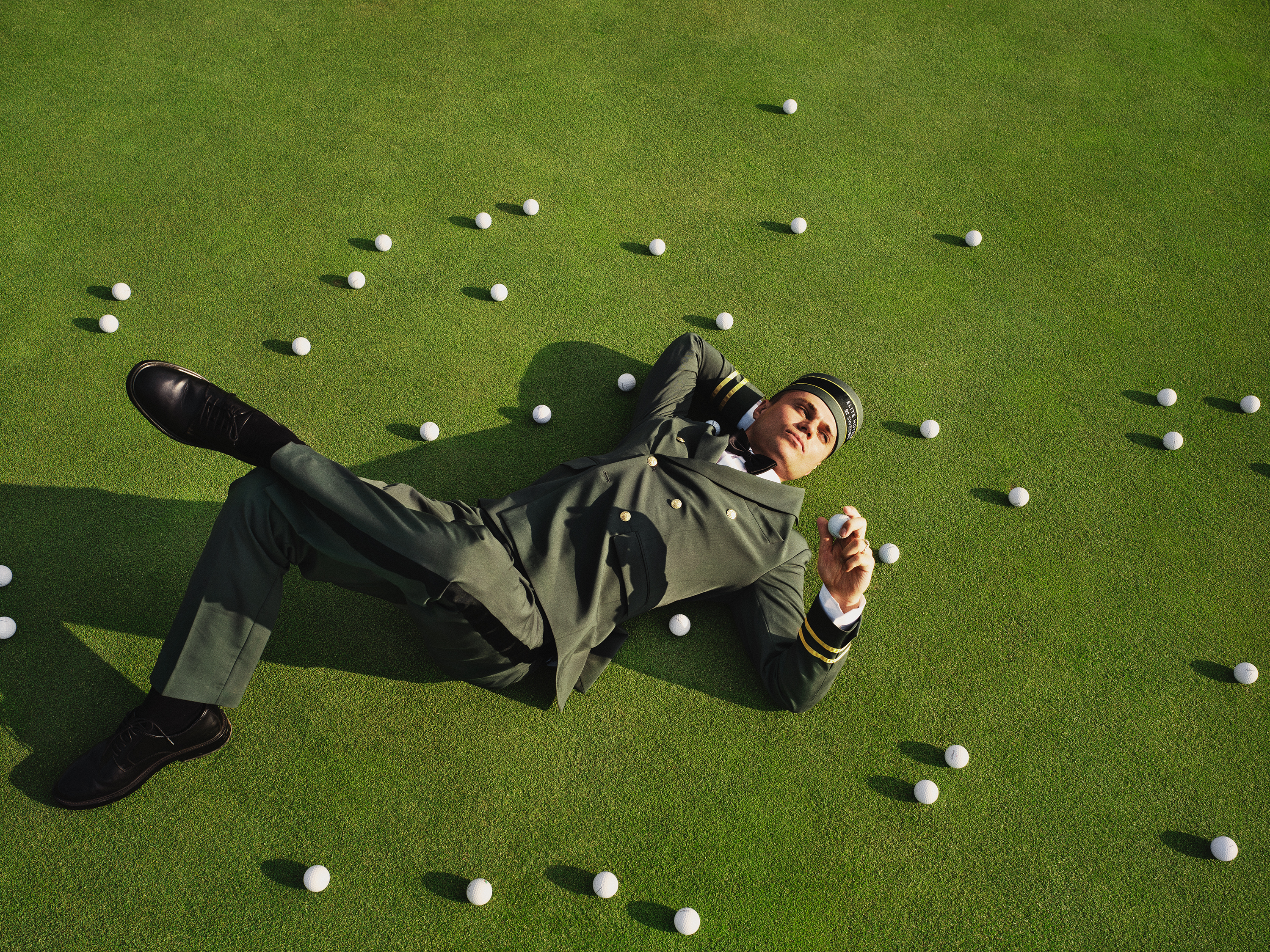 Person i uniform går på en golfbana med en golfbag över axeln.